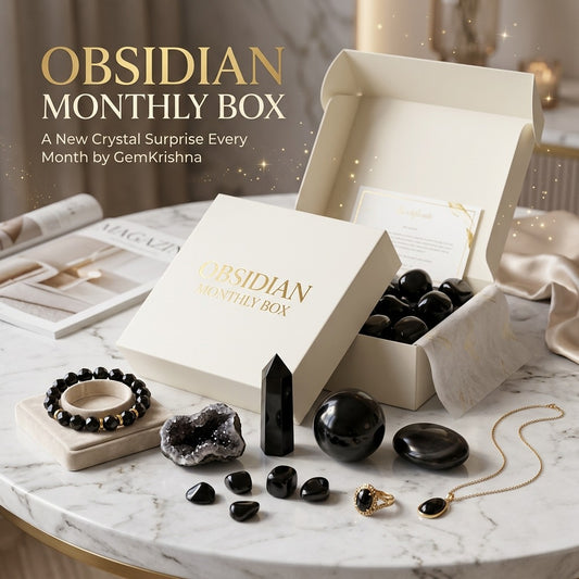 Obsidian Monthly Box with black crystal gifts, jewelry, and stones on marble table