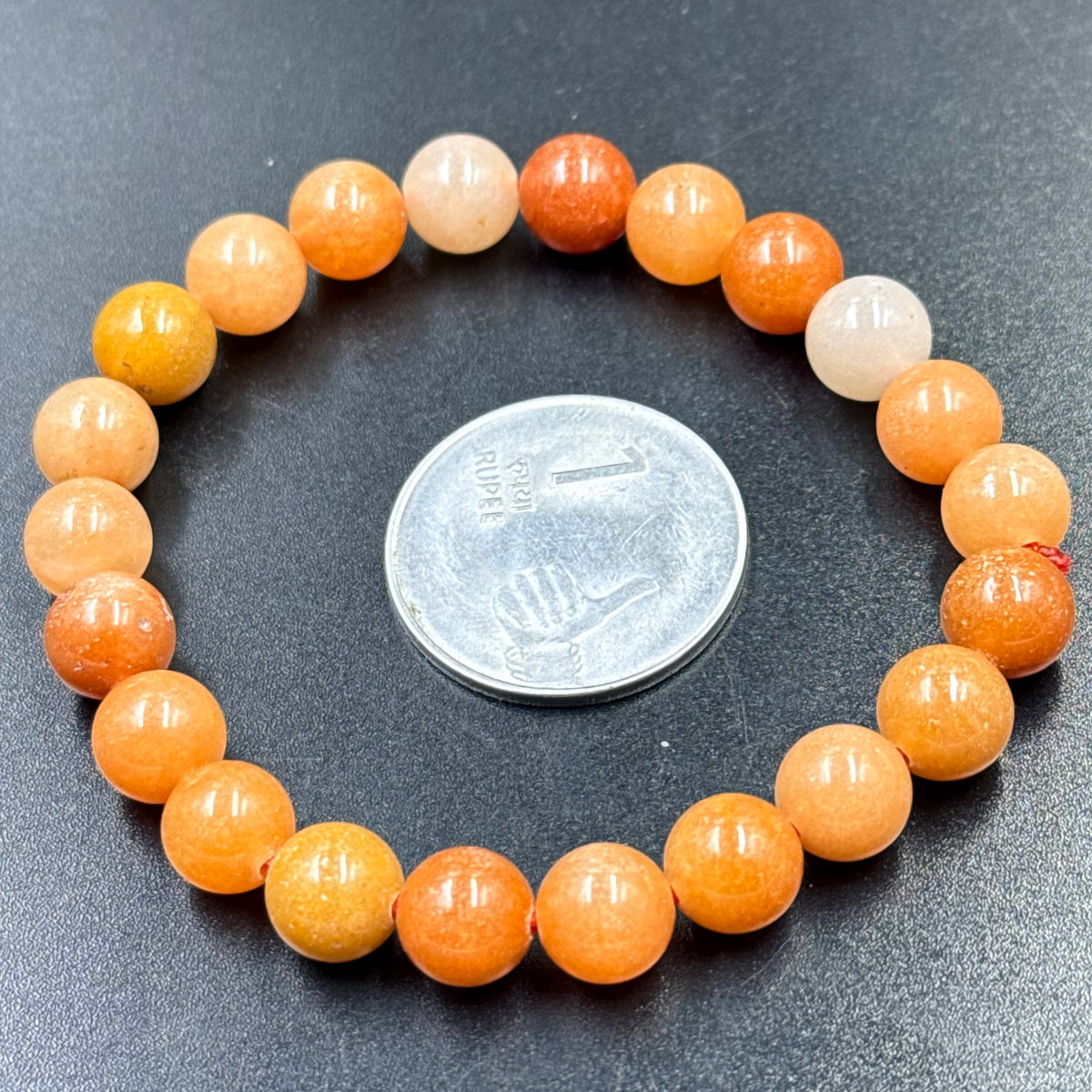 Close-up of orange aventurine beaded bracelet with round beads on dark background