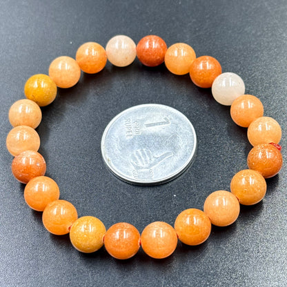 Close-up of orange aventurine beaded bracelet with round beads on dark background