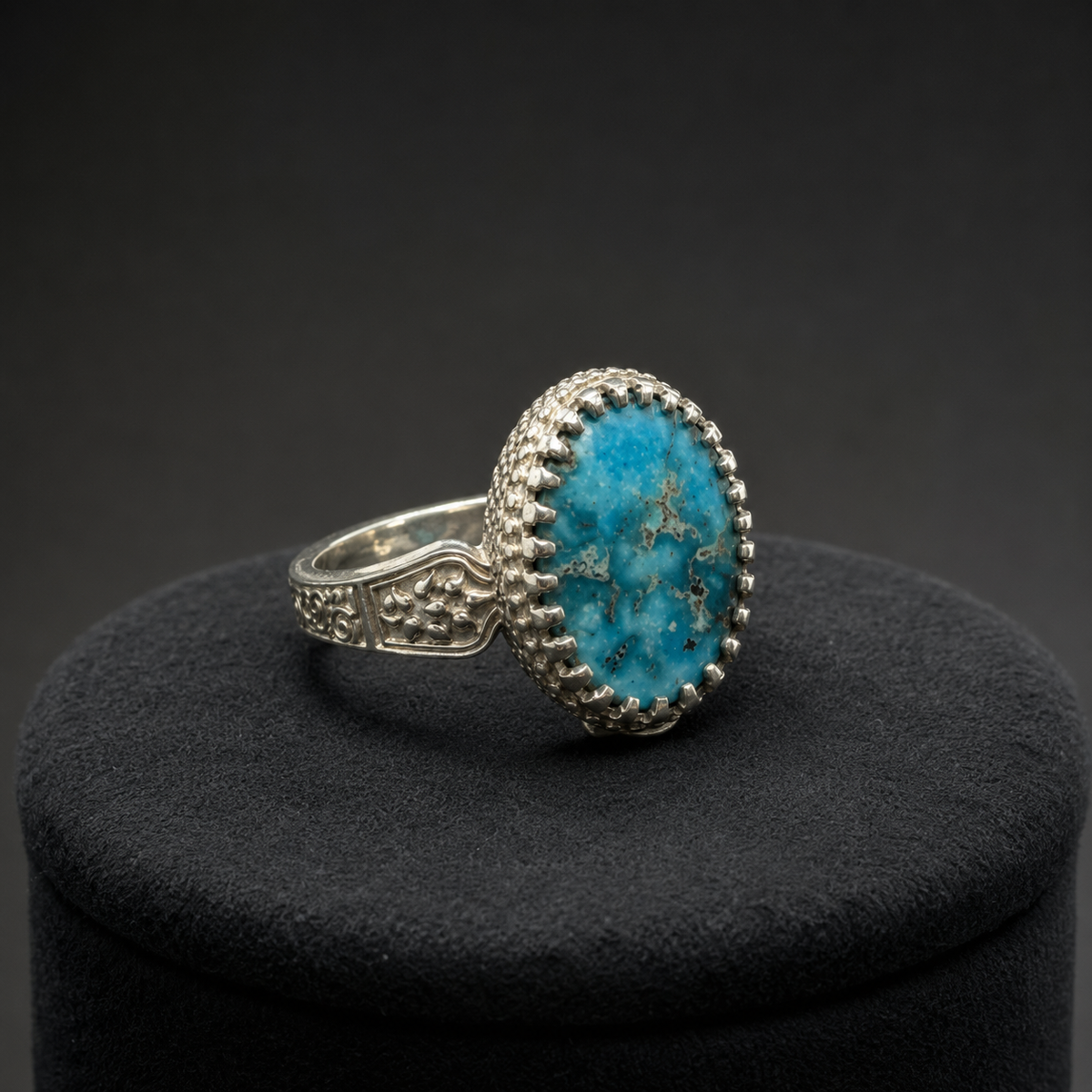 Oval turquoise statement ring on black display cushion with engraved silver band