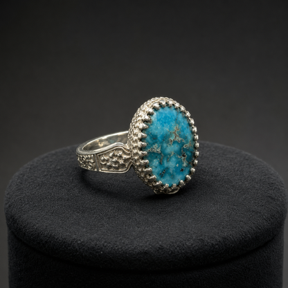 Oval turquoise statement ring on black display cushion with engraved silver band