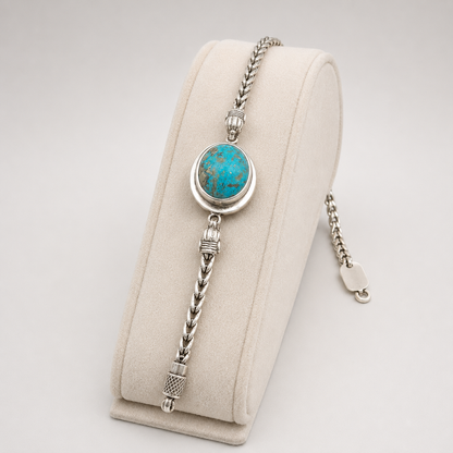 Oval turquoise 925 sterling silver bracelet displayed on beige velvet with blue oval stone centerpiece