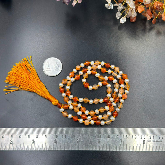 Pearl and carnelian jaap mala bead strands with tassel, shown with measuring ruler