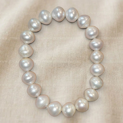 Pearl bracelet featuring large round pearls in soft pastel tones on beige cloth