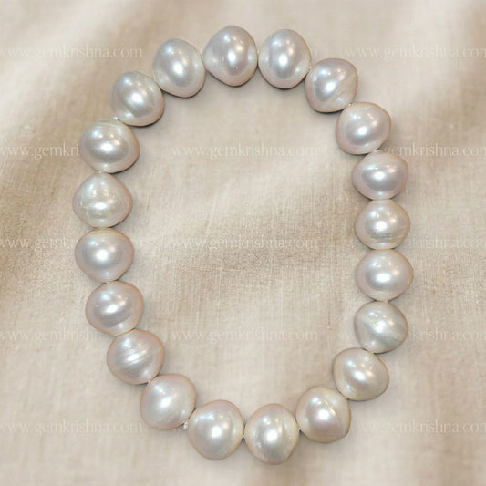 Pearl bracelet featuring large round pearls in soft pastel tones on beige cloth