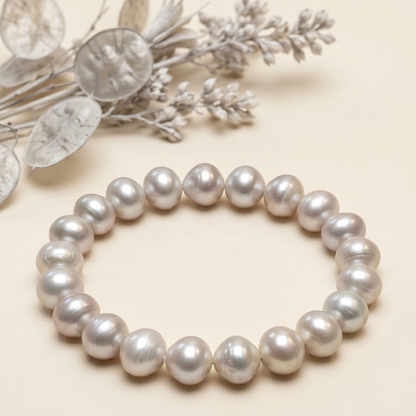 Pearl bracelet with round silvery pearls styled on soft beige fabric background