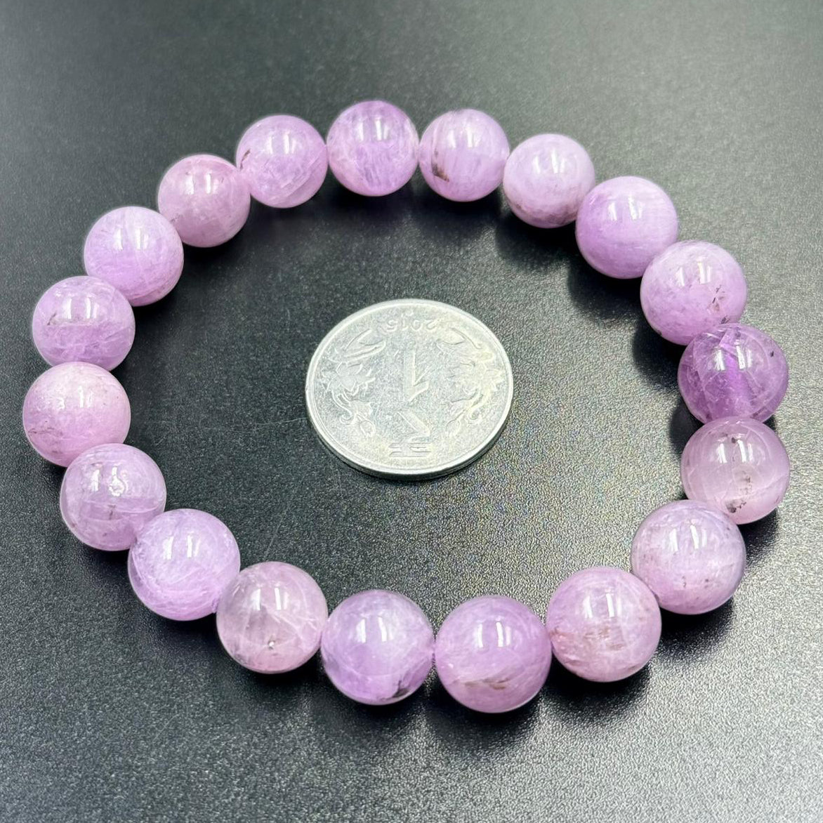 Pink Kunzite gemstone bead bracelet with round beads and visible size coin for scale