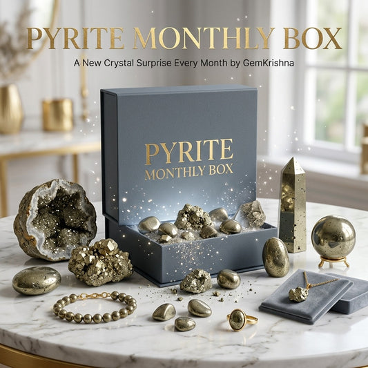 Pyrite Monthly Box with jewelry and pyrite crystal specimens on a marble surface