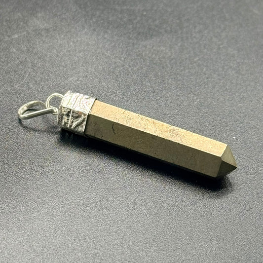 Pyrite pencil locket pendant with metal bail clasp on a gray surface