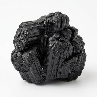 Raw black tourmaline crystal cluster with dark, prismatic facets on white background