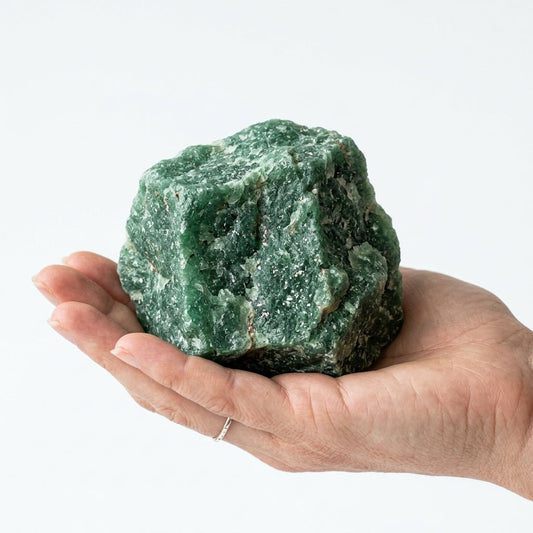 Raw green aventurine crystal held in a hand for size comparison