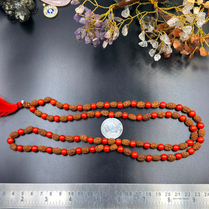 Red coral bead and rudraksha jap mala strands with red tassel shown on measuring board