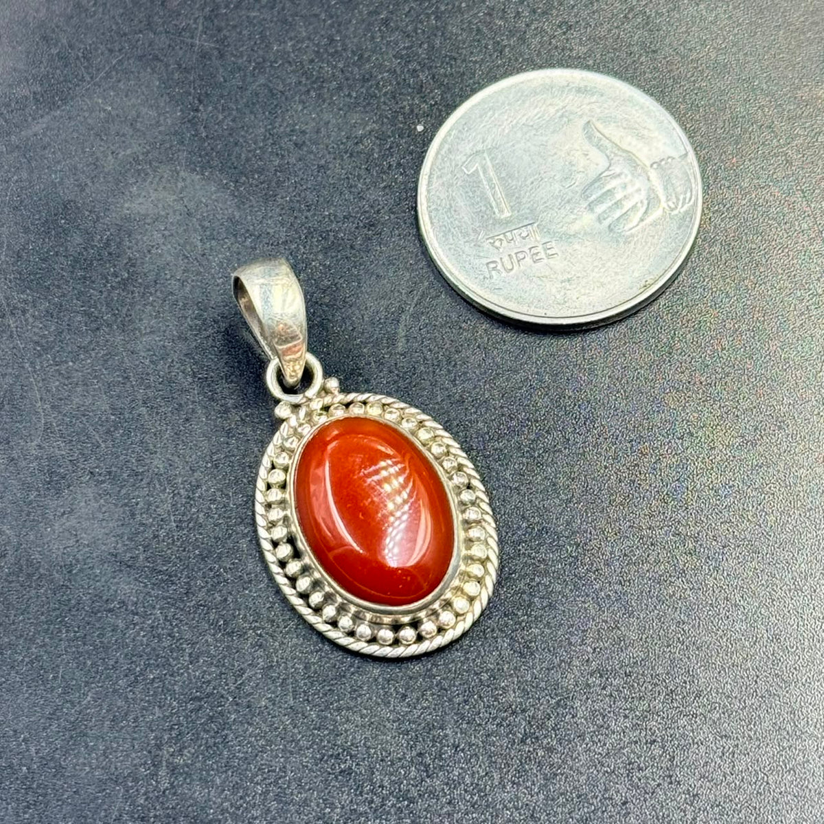 Red jasper oval locket pendant in 925 silver with beaded bezel on dark background