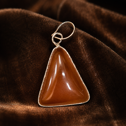 Red onyx locket pendant with silver-tone bail and loop clasp on dark fabric