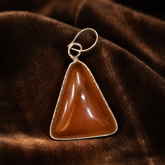 Red onyx locket pendant with silver-tone bail and loop clasp on dark fabric