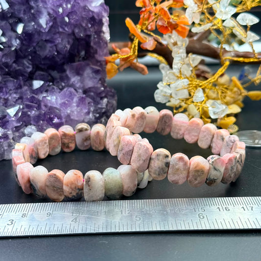 Rhodochrosite oval flat bead bracelet with pink and peach beads on a black surface and ruler