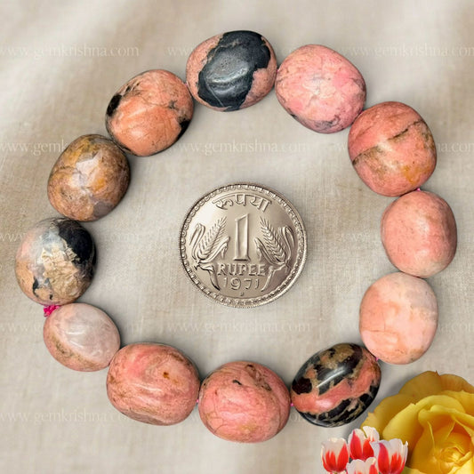 Rhodonite tumble bead bracelet close-up with oval pink and black stones and a coin for scale