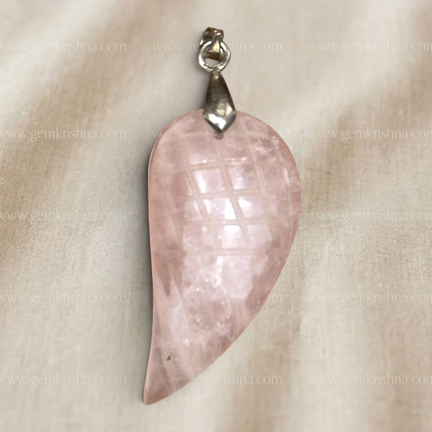 Rose quartz feather-wing locket pendant close up with silver bail on light fabric