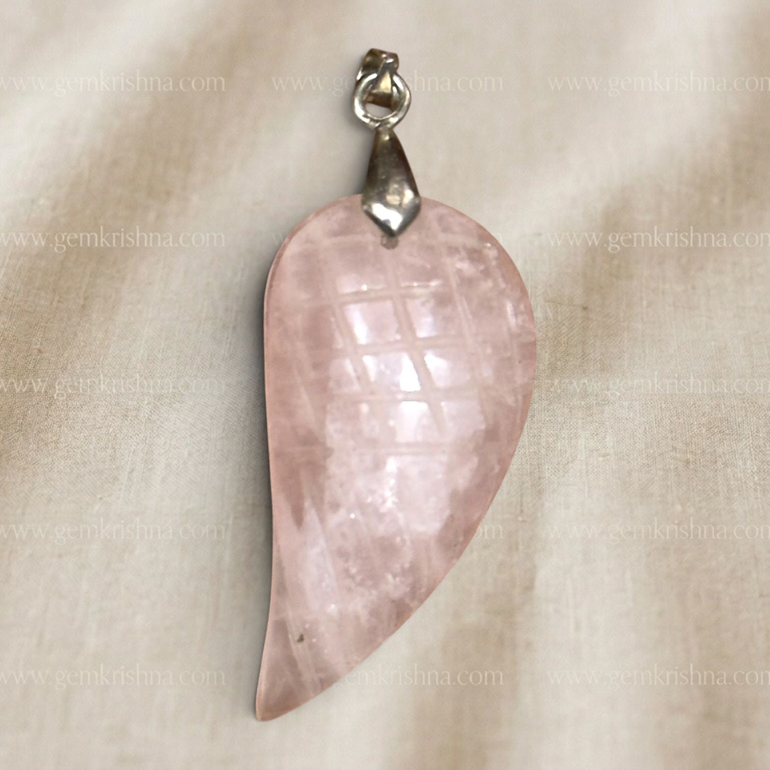 Rose quartz feather-wing locket pendant close up with silver bail on light fabric
