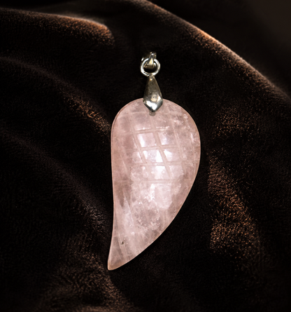Rose quartz feather-wing locket pendant with silver bail on dark velvet background