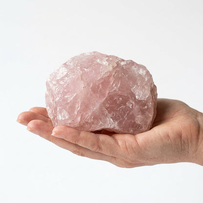 Raw rose quartz crystal held in a hand, natural pink stone rough surface