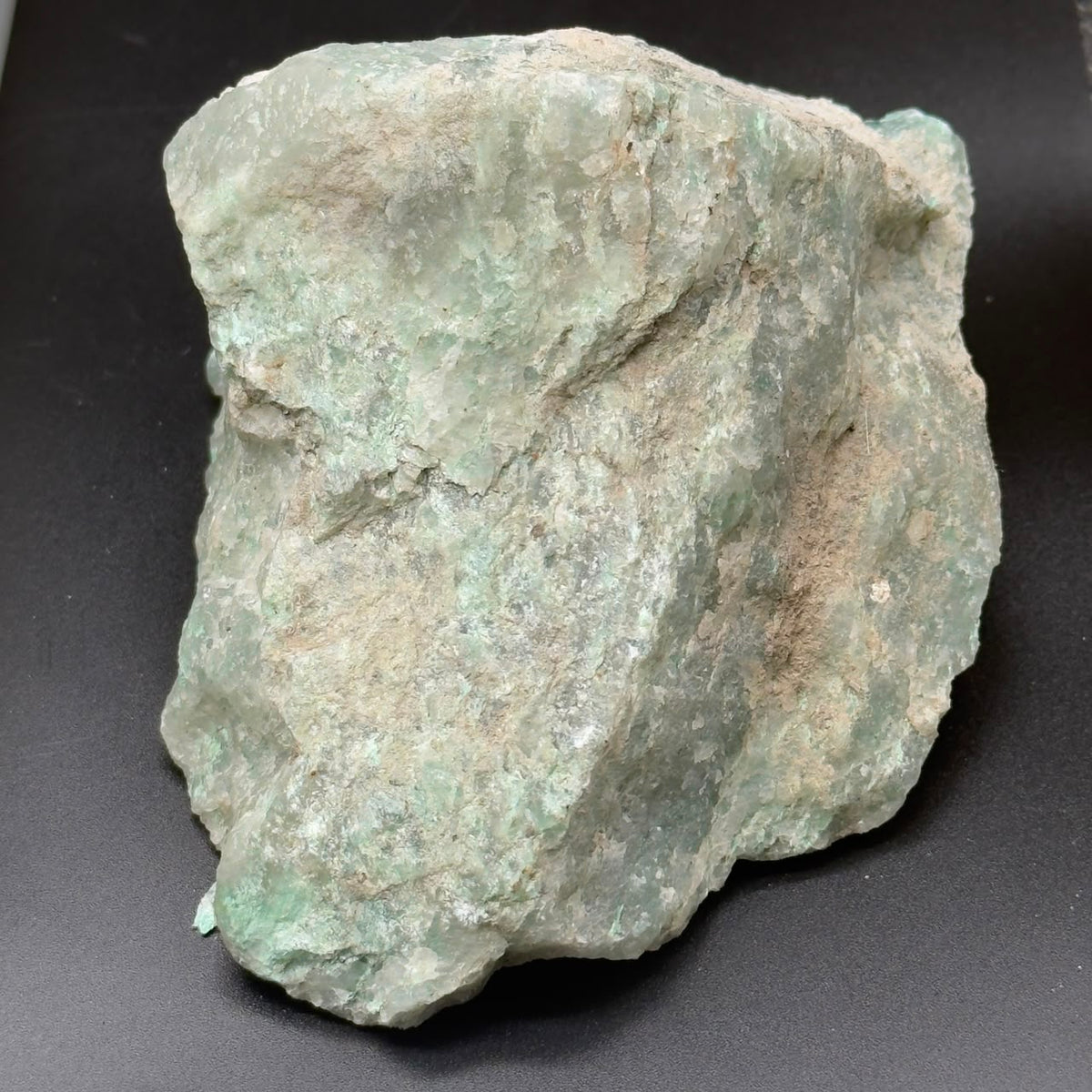 Unpolished rough Amazonite chunk with pale aqua and white tones on dark background