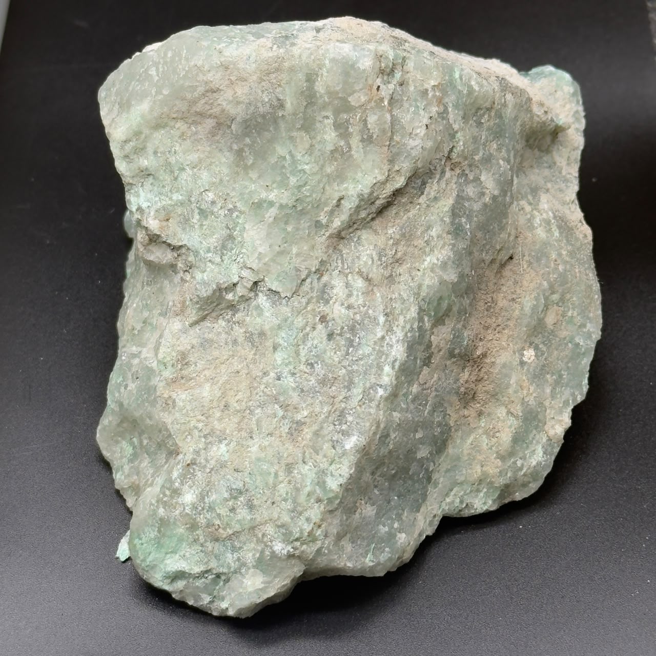 Unpolished rough Amazonite chunk with pale aqua and white tones on dark background