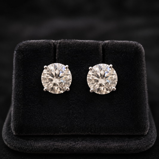 Round moissanite stud earrings in 925 silver with four-prong settings on black velvet display