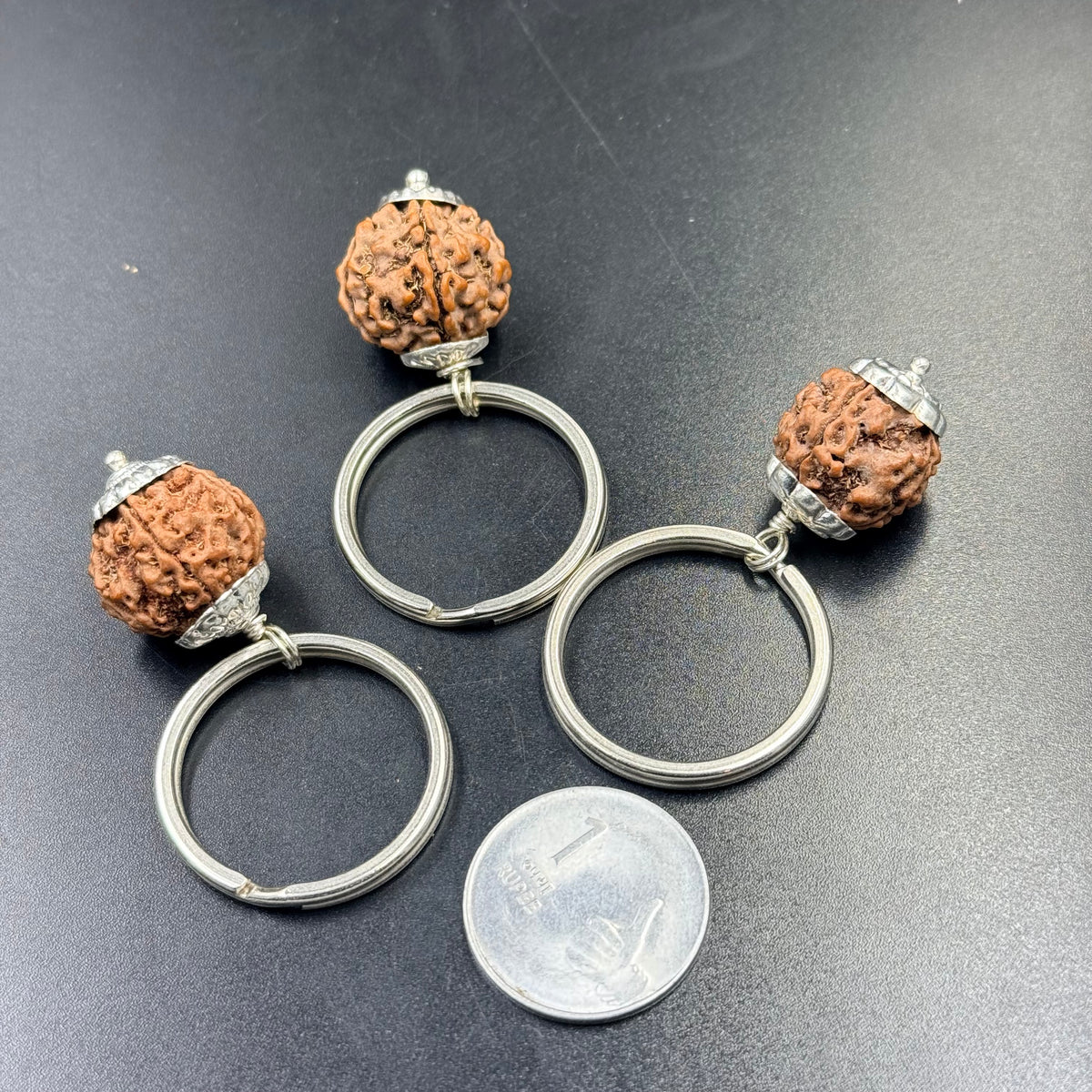 Rudraksha keychain with 4 5 6 mukhi pendant and silver-tone rings on blue surface