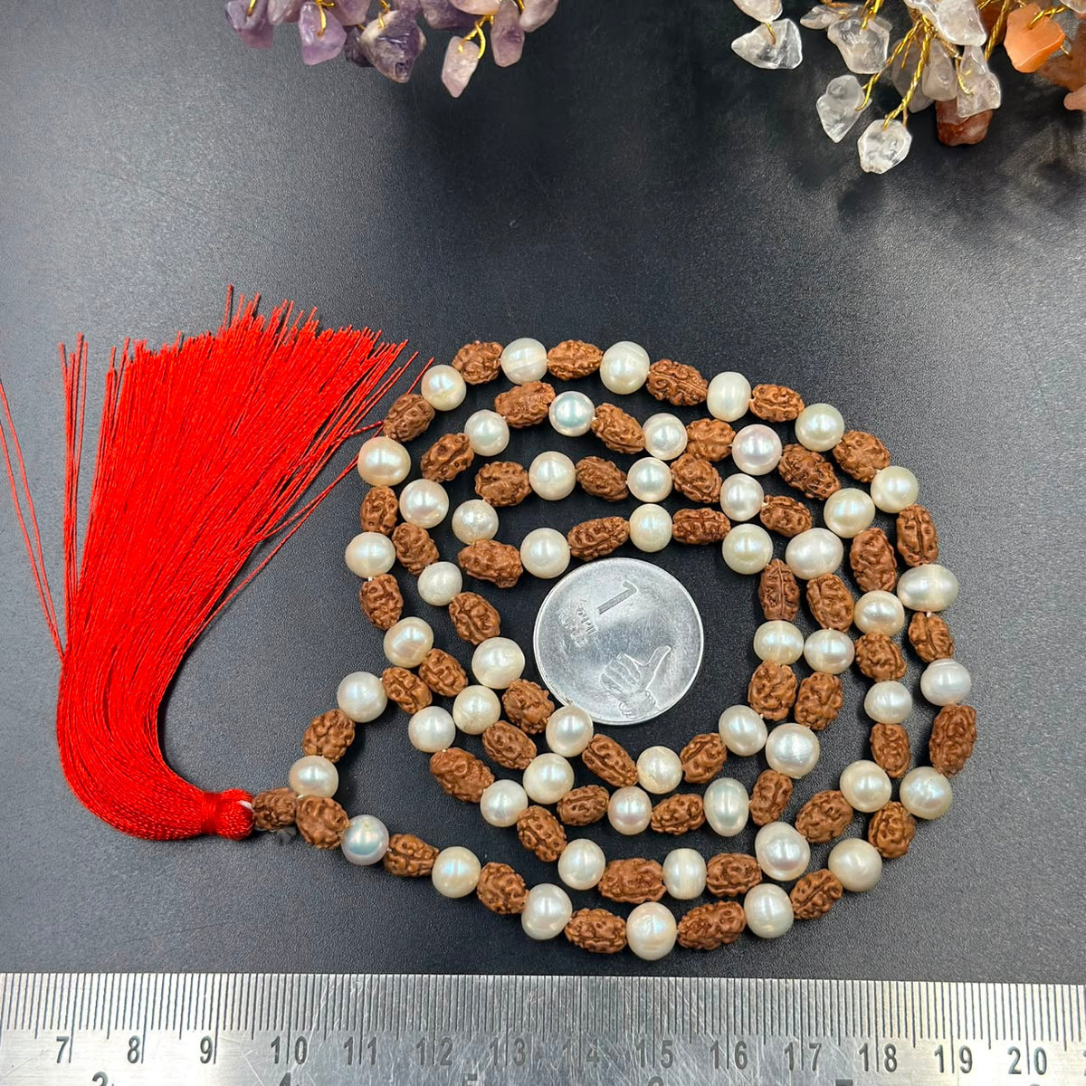 Rudraksha and 6mm pearl japa mala with red tassel laid on dark fabric