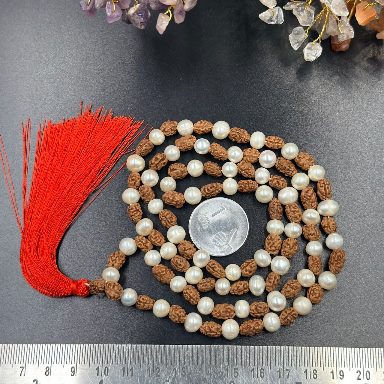 Rudraksha and 6mm pearl japa mala with red tassel laid on dark fabric