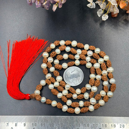 Rudraksha and 6mm pearl japa mala with red tassel laid on dark fabric