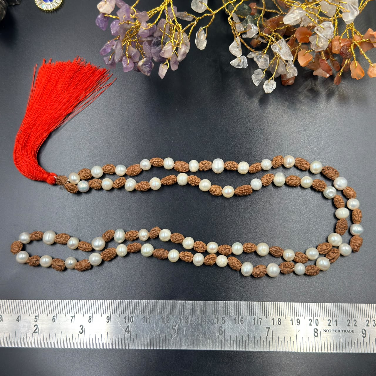 Rudraksha and 6mm pearl japa mala strands with red tassel on dark surface