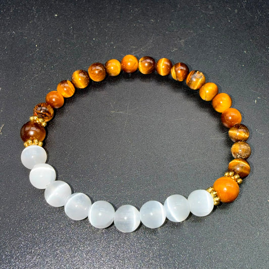 Selenite and tiger eye bead bracelet with gold spacers on dark textured background