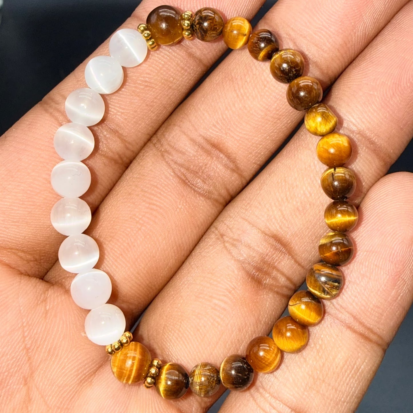 Selenite and tiger eye bracelet beads shown on open palm
