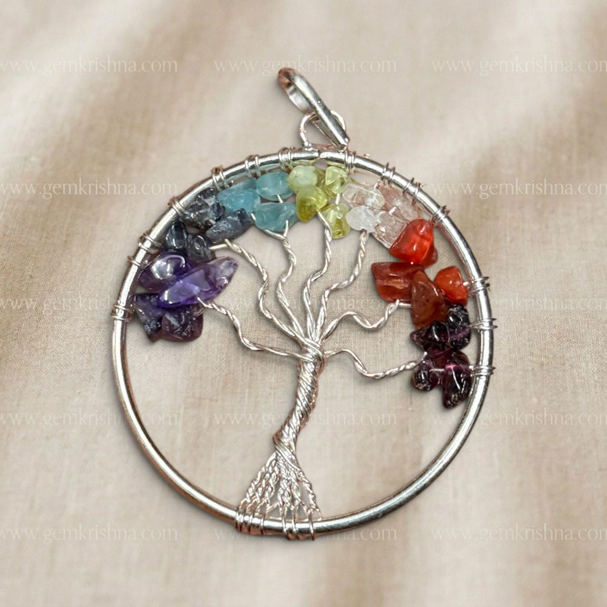 Close-up of seven chakra tree locket pendant with silver wire branches and multi-color stones