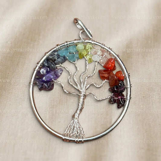 Close-up of seven chakra tree locket pendant with silver wire branches and multi-color stones
