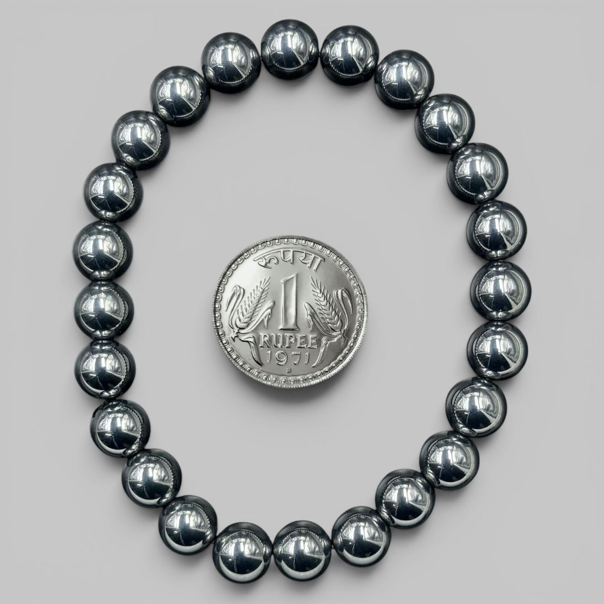 Shungite Elite bracelet view with shiny black round beads and rup ee coin for scale