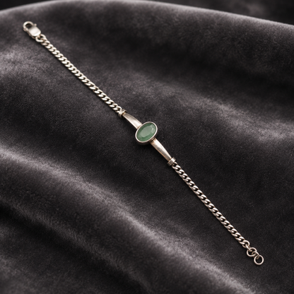 Silver bracelet with green emerald panna center and chain clasp on dark velvet