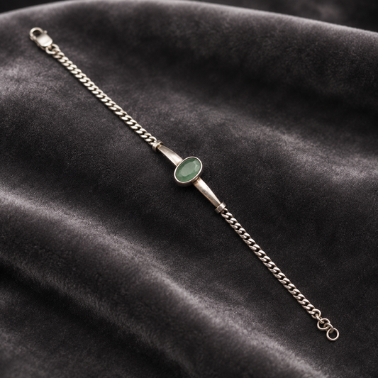 Silver bracelet with green emerald panna center and chain clasp on dark velvet