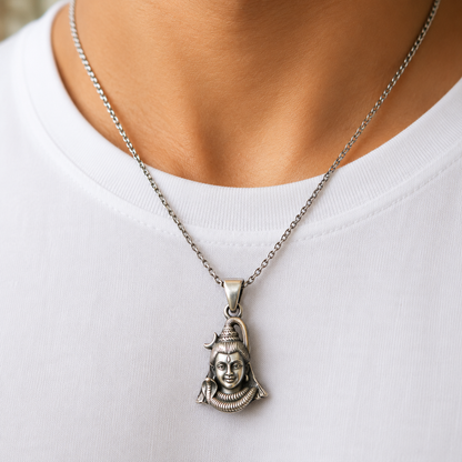 Lord Shiva face pendant on silver chain worn on a white shirt