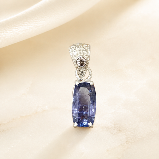 Natural tanzanite and lab-grown diamond pendant close-up on light fabric background