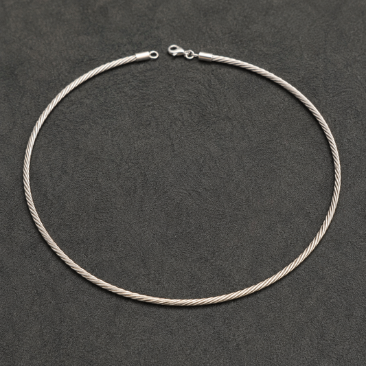 Silver Italian-style twisted hasli necklace with clasp and chain links laid on dark background