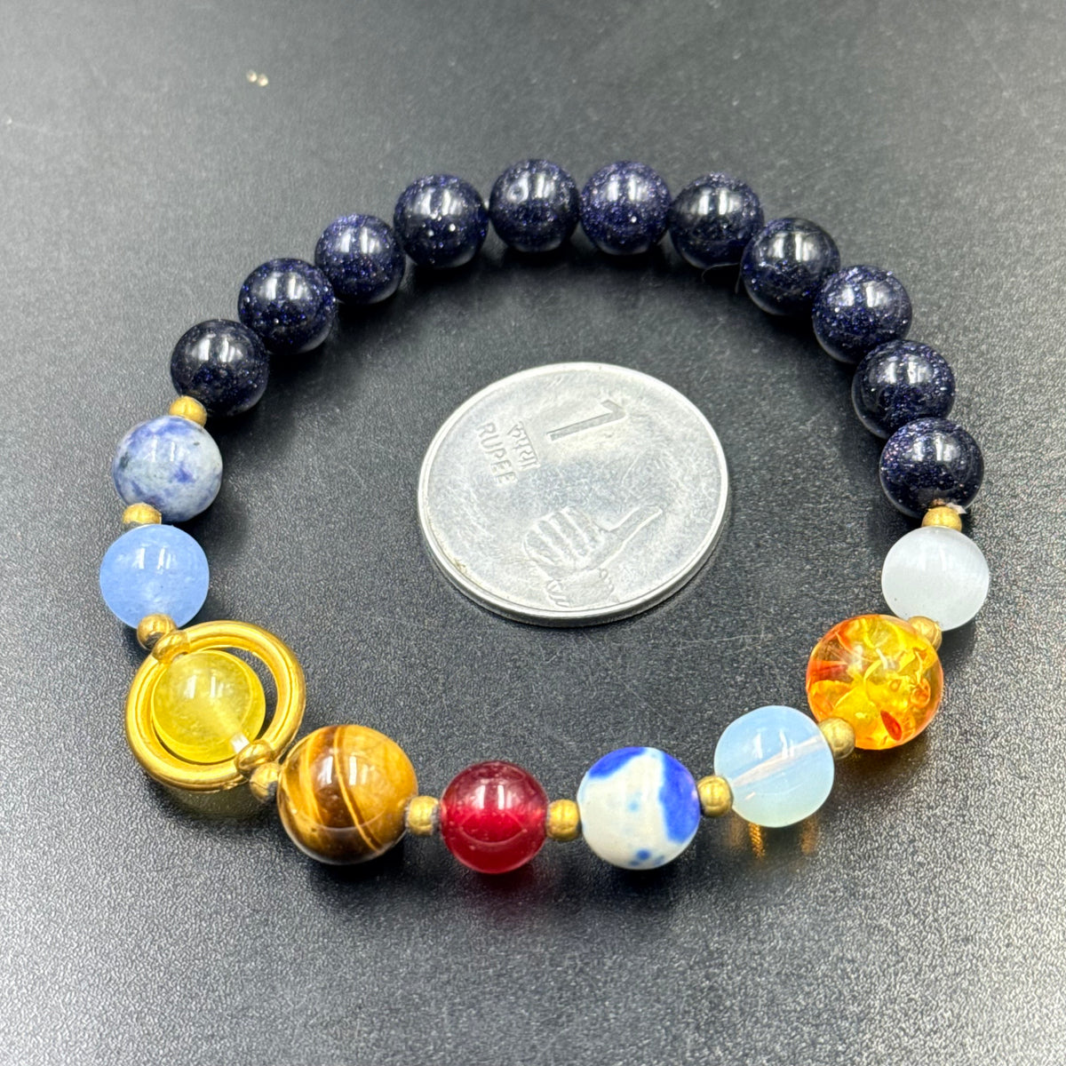 Close-up of solar system bracelet with dark blue beads and colorful planetary accent beads