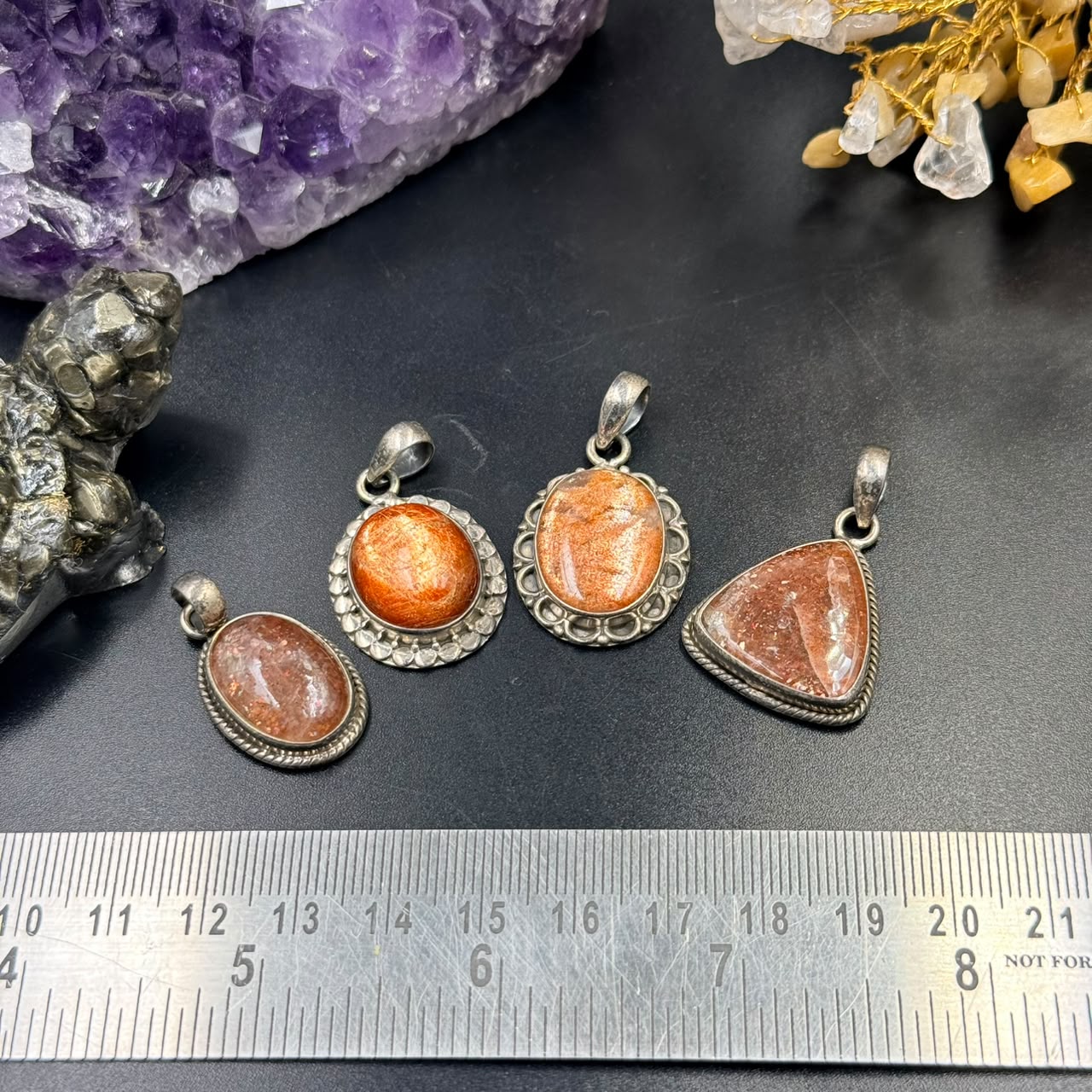 Oval sunstone silver locket pendant with textured bezel, shown on dark stone background
