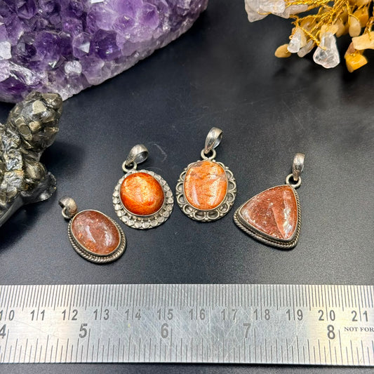 Oval sunstone silver locket pendant with textured bezel, shown on dark stone background