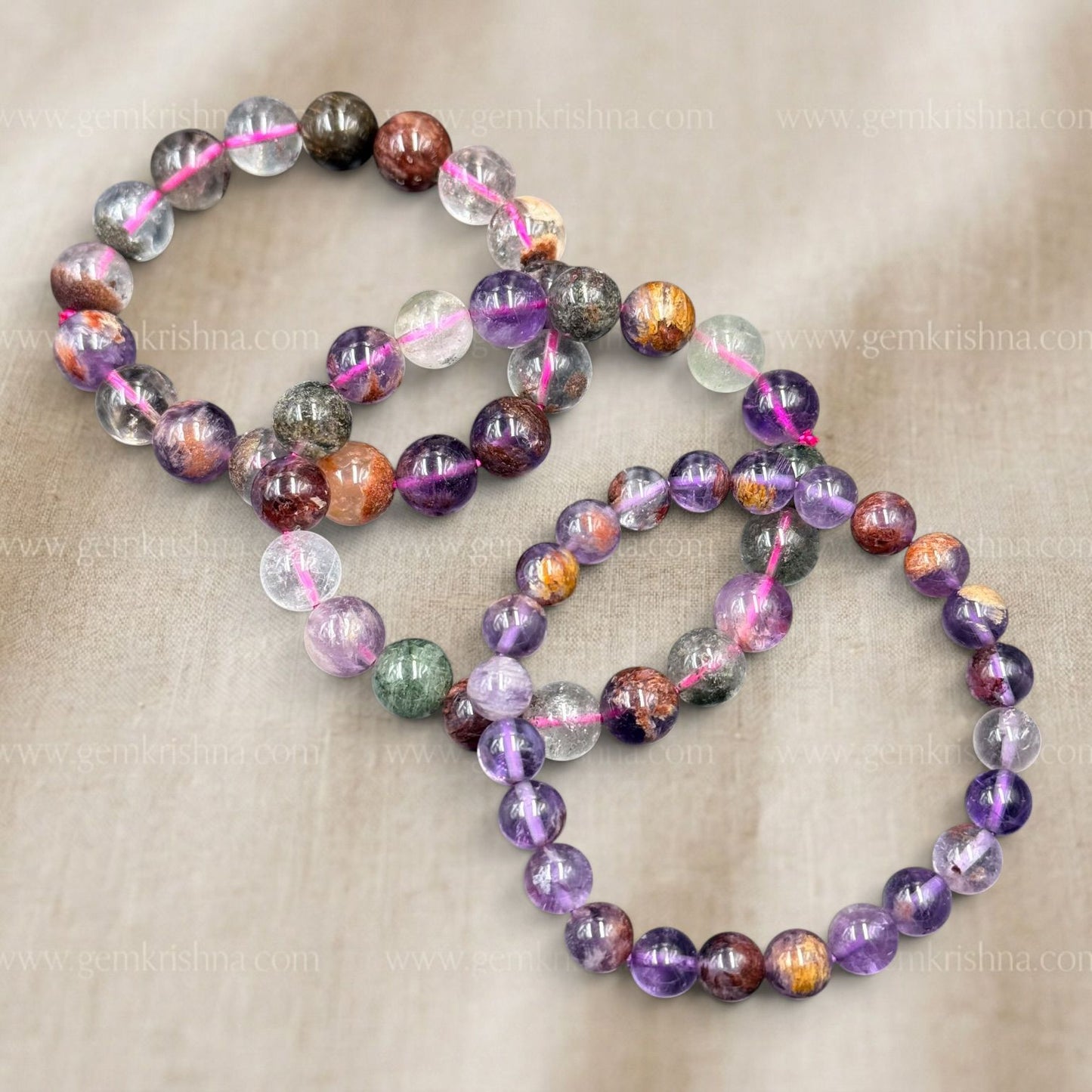 Super Seven Bracelet laid out with multicolor stone beads on beige fabric background