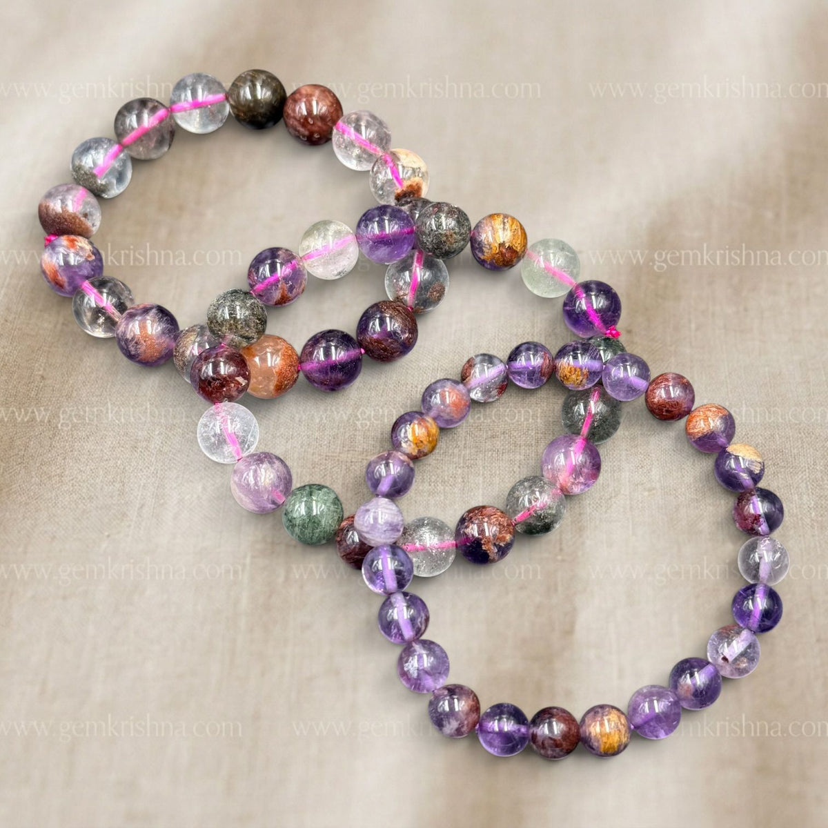 Super Seven Bracelet laid out with multicolor stone beads on beige fabric background