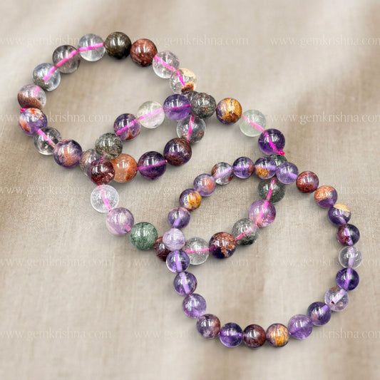 Super Seven Bracelet laid out with multicolor stone beads on beige fabric background