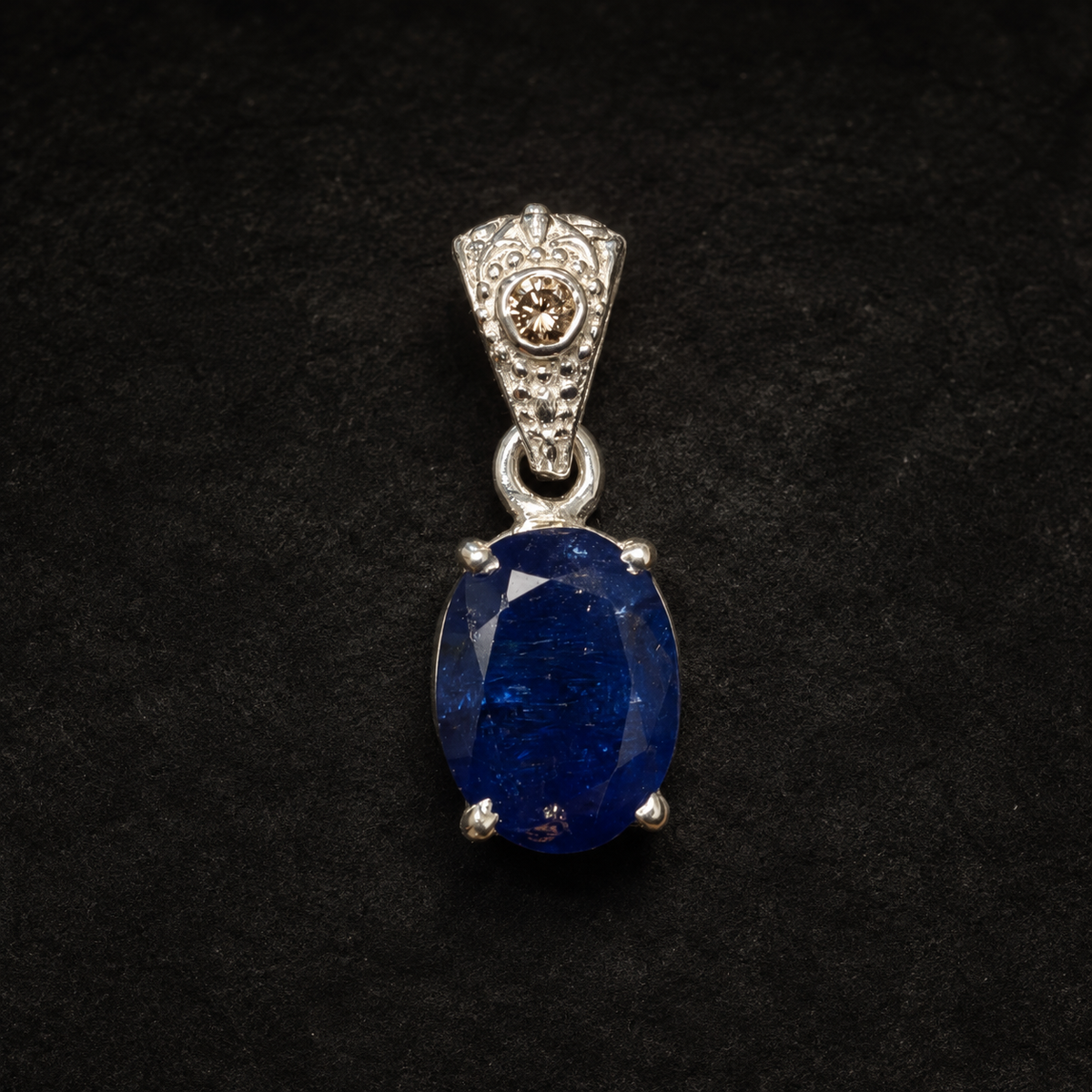 Close-up natural tanzanite and lab-grown diamond pendant in 925 silver on black background